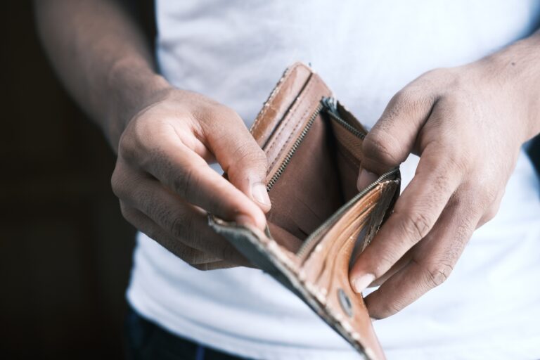 Mężczyzna trzyma w dłoni portfel bez pieniędzy